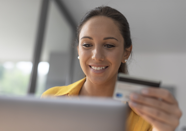 Frau sitzt vor einem Laptop und bezahlt online mit einer Kreditkarte