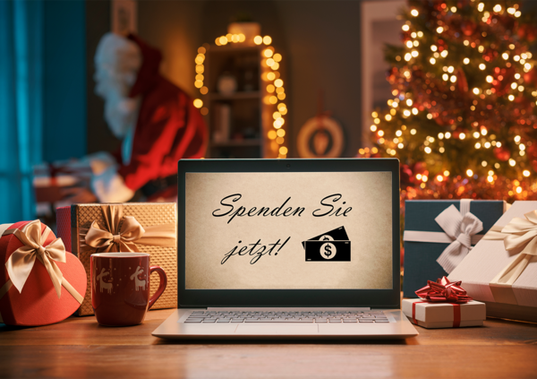Laptop mit Spendenaufruf auf einem Tisch vor einem Weihnachtsbaum