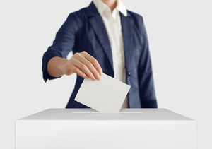 Frau steckt Wahlkarte in eine Wahlbox