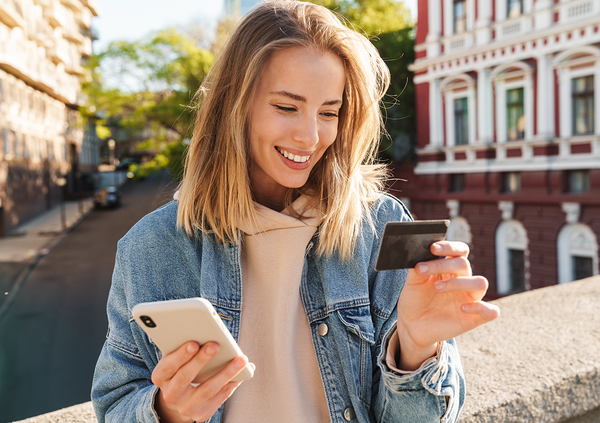 Eine Frau h&auml;lt eine Kreditkarte und ein Smartphone in der Hand