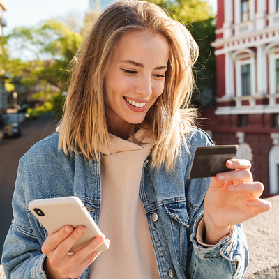 Eine Frau h&auml;lt eine Kreditkarte und ein Smartphone in der Hand