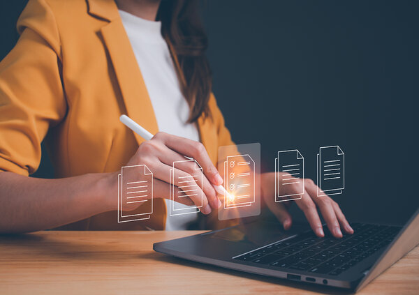 Eine Person sitzt an einem Laptop und bearbeitet elektronische Dokumente