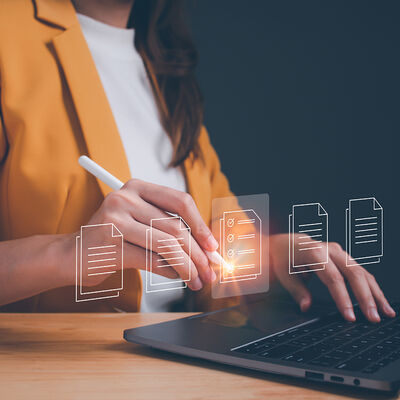 Eine Person sitzt an einem Laptop und bearbeitet elektronische Dokumente
