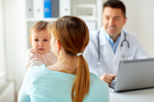 Eine Mutter h&auml;lt ihr Baby auf dem Arm und spricht mit einem Arzt