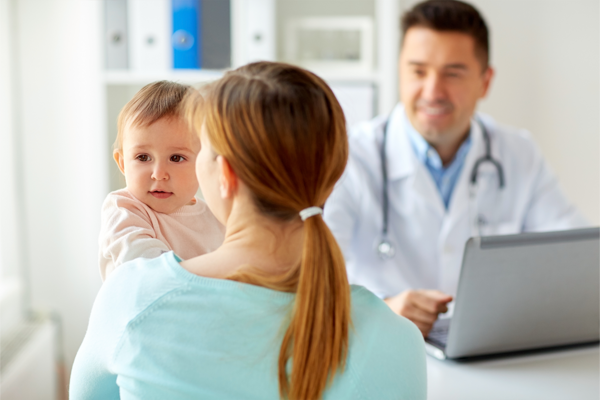 Eine Mutter h&auml;lt ihr Baby auf dem Arm und spricht mit einem Arzt