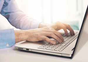 Mann gibt Daten in einen Laptop ein
